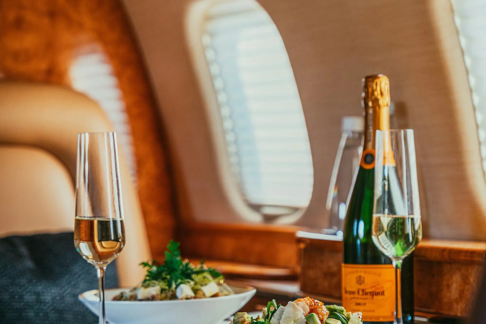 A plated lunch and champagne on a white tablecloth beside a cabin window