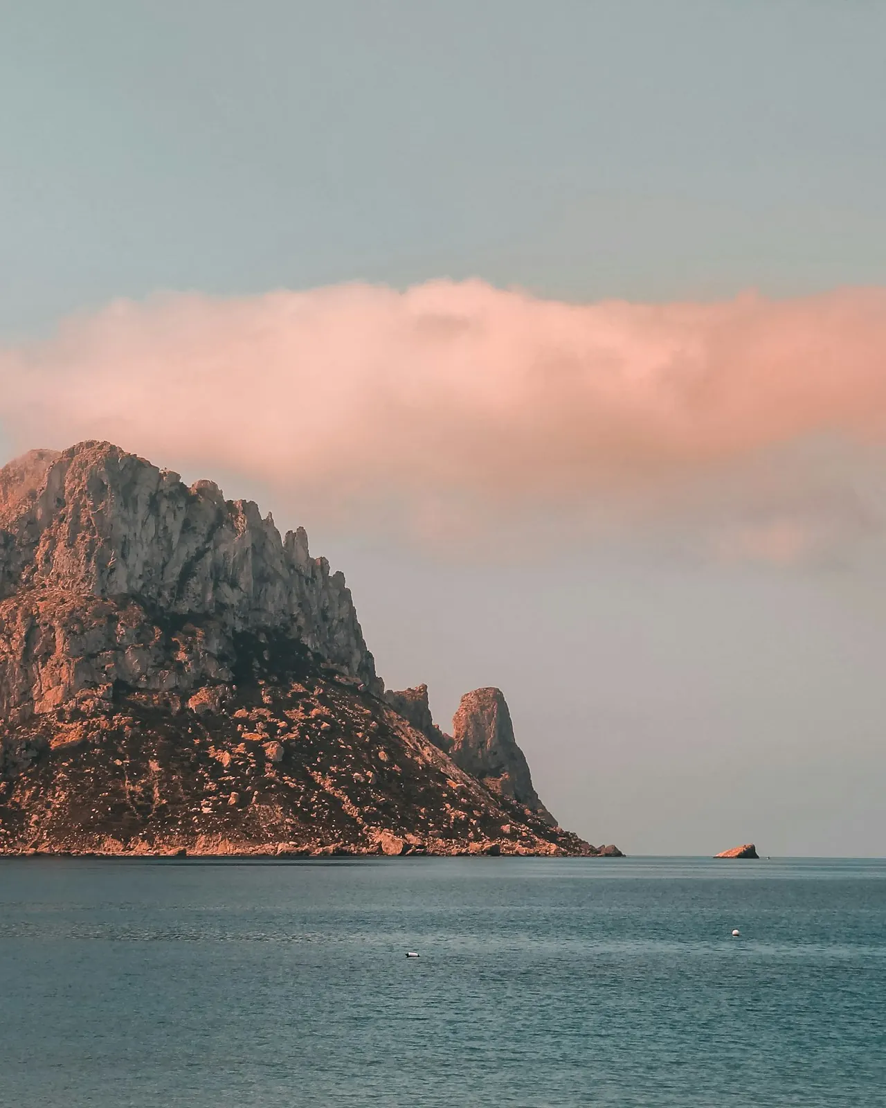 The island of Es Vedrà off Ibiza under a pink evening sky