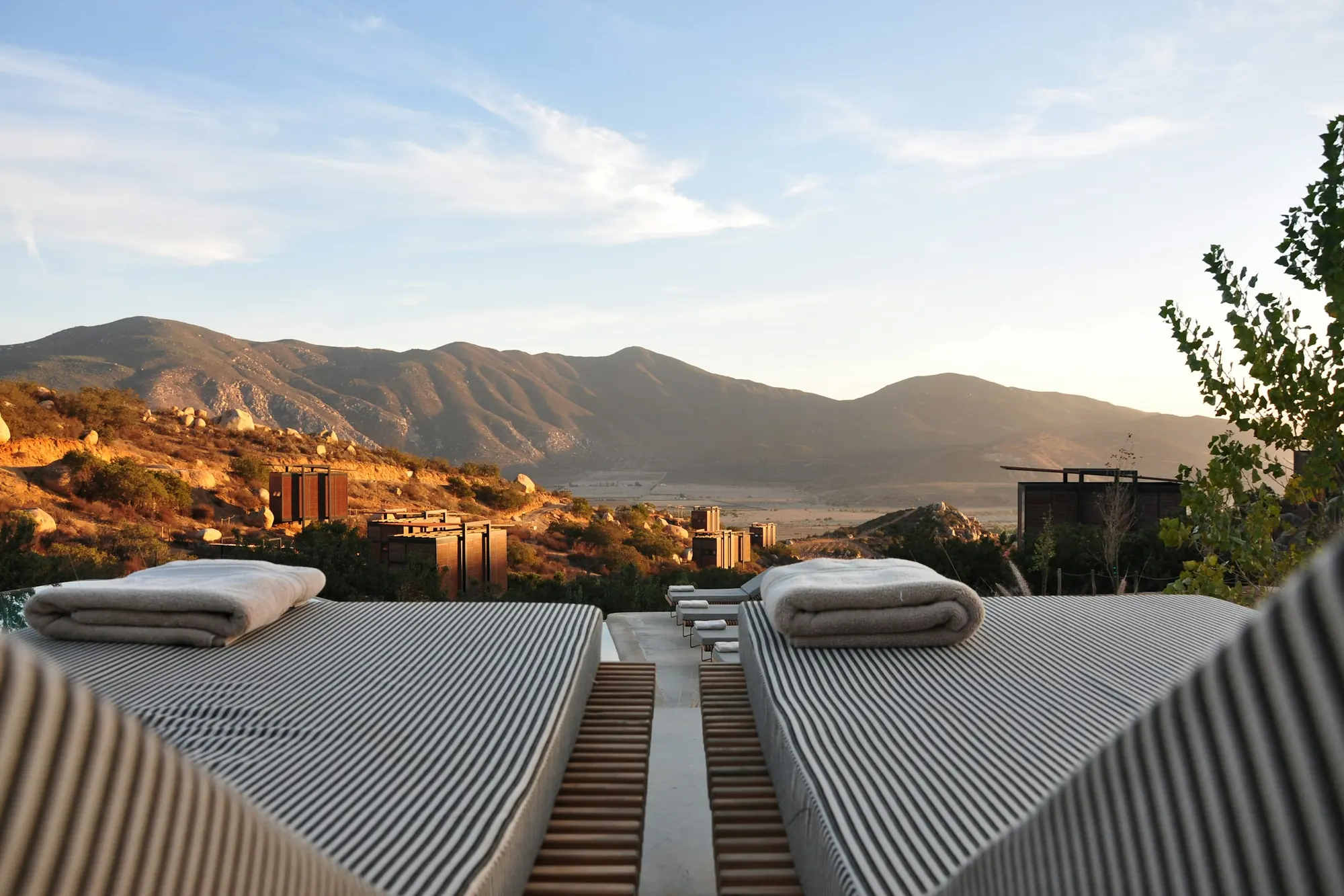 Two sun loungers on a terrace looking out over mountains at golden hour
